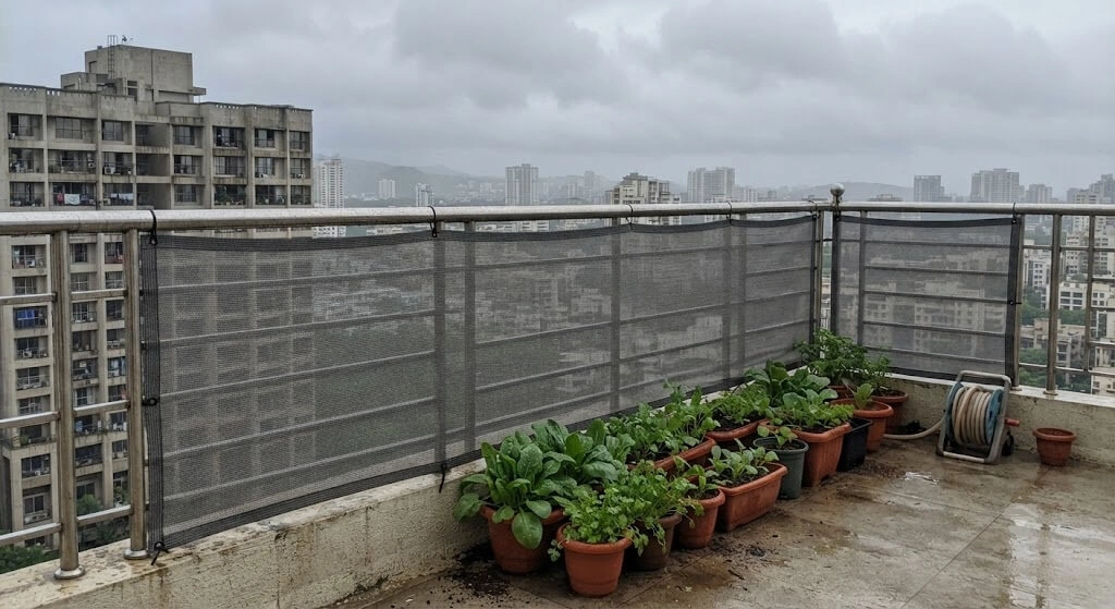 Windbreak mesh protecting rooftop plants during monsoon season